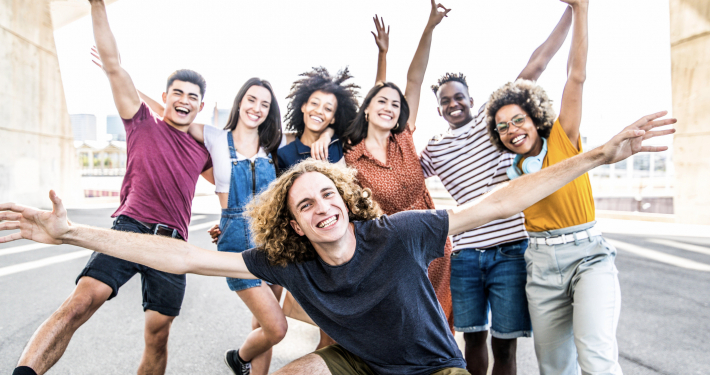Große Gruppe glücklicher Freunde steht auf der Straße mit erhobenen Armen zusammen