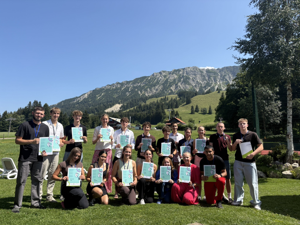Pierre-de-Coubertin-Teilnehmende mit Urkunde vor Alpenpanorama